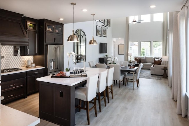 kitchen with appliances with stainless steel finishes, a kitchen island, tasteful backsplash, a kitchen bar, and decorative light fixtures