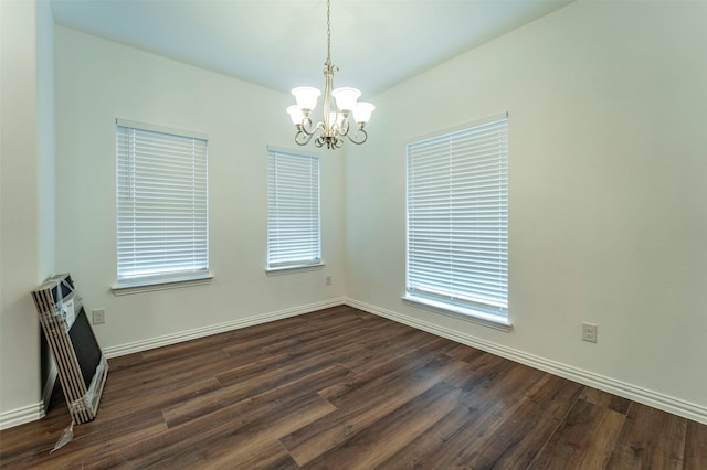 unfurnished room featuring a healthy amount of sunlight, dark hardwood / wood-style flooring, and a notable chandelier