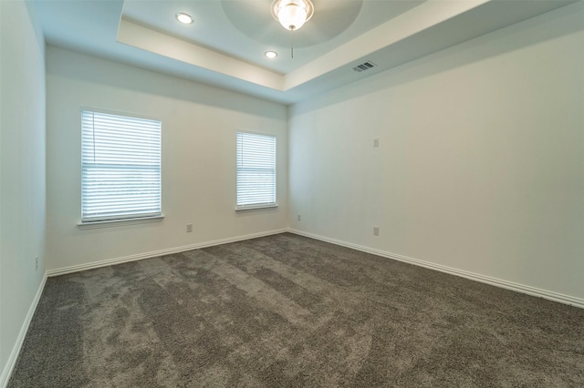 carpeted empty room with a raised ceiling and ceiling fan