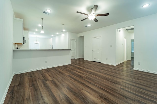 unfurnished living room featuring ceiling fan with notable chandelier and dark hardwood / wood-style floors