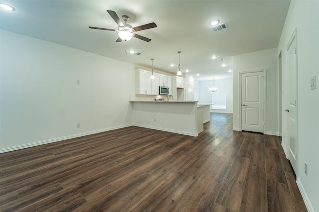 unfurnished living room featuring sink, ceiling fan with notable chandelier, and dark hardwood / wood-style flooring