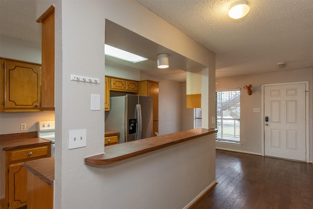 kitchen with dark wood-type flooring, a textured ceiling, stainless steel fridge, kitchen peninsula, and white range with electric cooktop