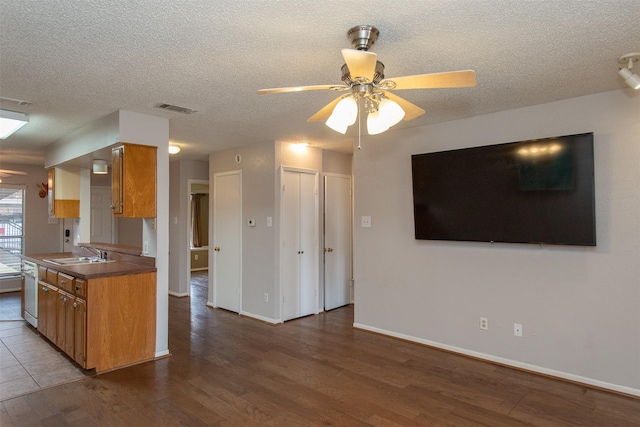 kitchen featuring dark wood-type flooring, brown cabinets, visible vents, and a sink