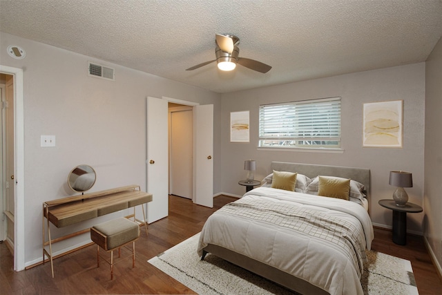 bedroom with ceiling fan, dark hardwood / wood-style floors, and a textured ceiling