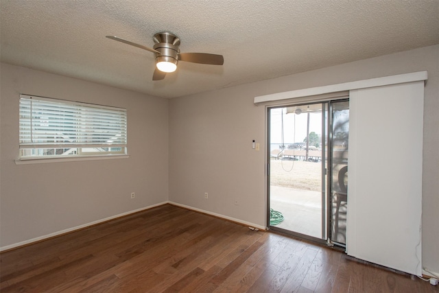 empty room with dark wood finished floors, a textured ceiling, baseboards, and ceiling fan