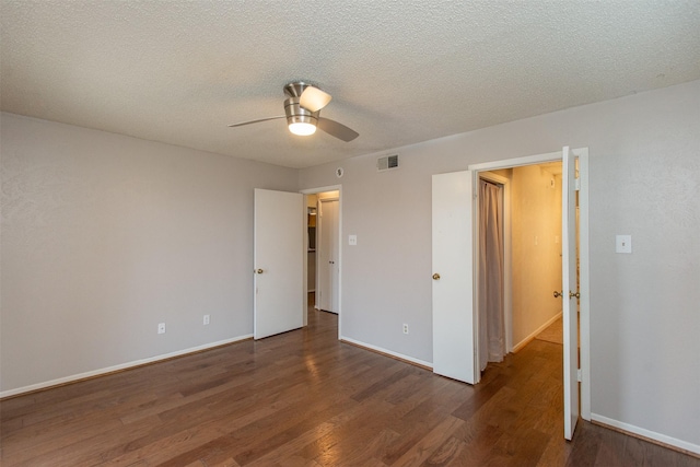 unfurnished bedroom featuring baseboards, wood finished floors, visible vents, and a textured ceiling