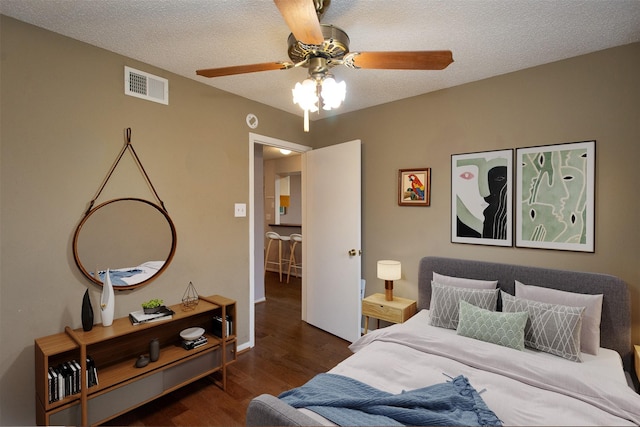 bedroom featuring visible vents, a textured ceiling, ceiling fan, and wood finished floors