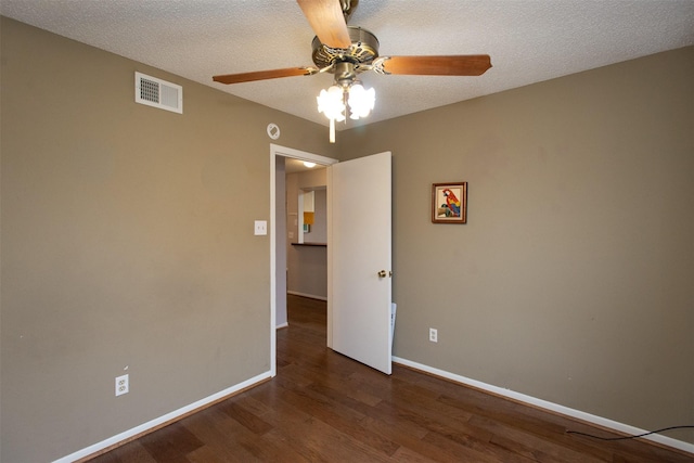 empty room with wood finished floors, baseboards, visible vents, ceiling fan, and a textured ceiling