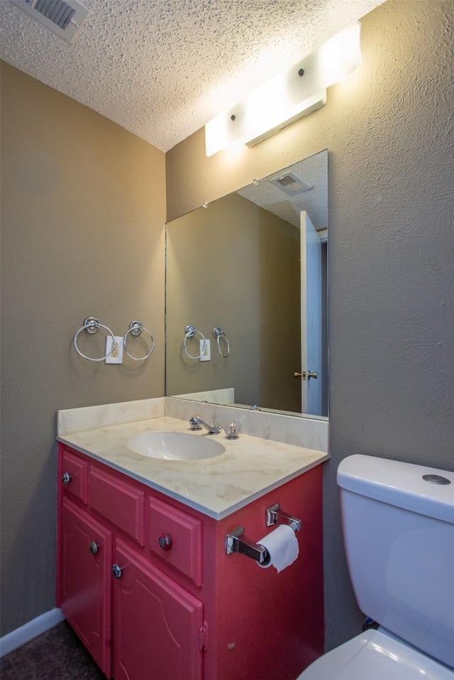 bathroom with vanity, a textured ceiling, and toilet