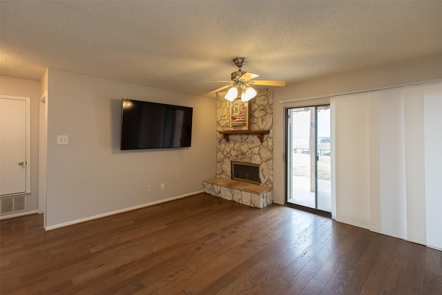 unfurnished living room featuring wood finished floors, visible vents, a fireplace, ceiling fan, and a textured ceiling