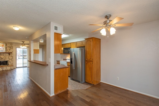 kitchen featuring wood finished floors, stainless steel fridge, ceiling fan, and black microwave