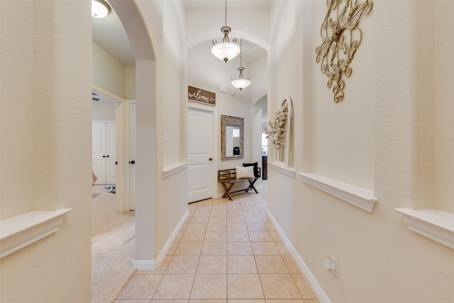 hallway with a high ceiling and light tile patterned floors