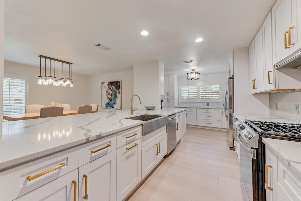 kitchen with white cabinetry, sink, light stone counters, and stainless steel appliances