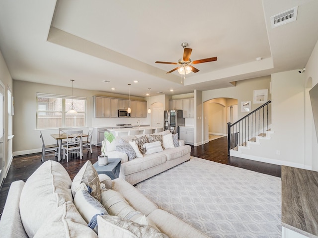 3124 Creek Meadow Dr, Anna, TX 75409 - living area with visible vents, arched walkways, dark wood finished floors, stairway, and a tray ceiling