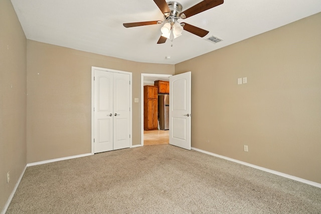 unfurnished bedroom featuring freestanding refrigerator, light colored carpet, and baseboards