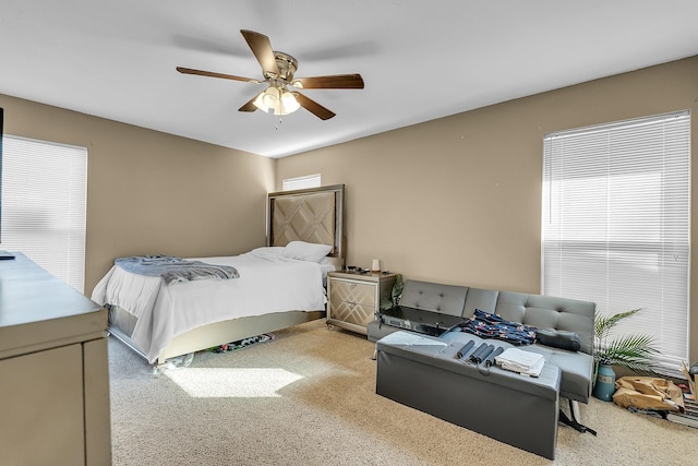 bedroom featuring ceiling fan, light carpet, and multiple windows