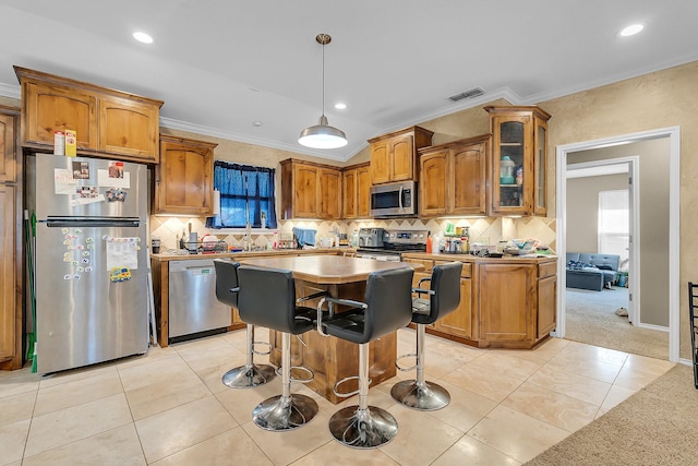 kitchen with ornamental molding, appliances with stainless steel finishes, a center island, and decorative light fixtures