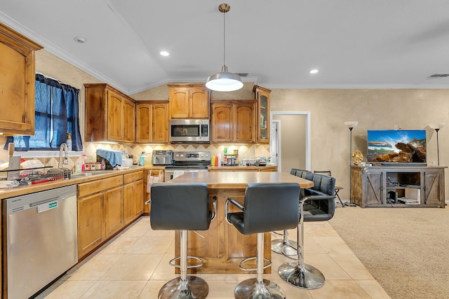 kitchen with sink, appliances with stainless steel finishes, a center island, ornamental molding, and light tile patterned flooring