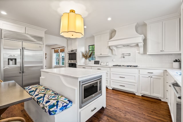 kitchen featuring premium range hood, white cabinetry, and built in appliances