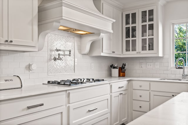 kitchen with stainless steel gas cooktop, sink, custom exhaust hood, and white cabinets