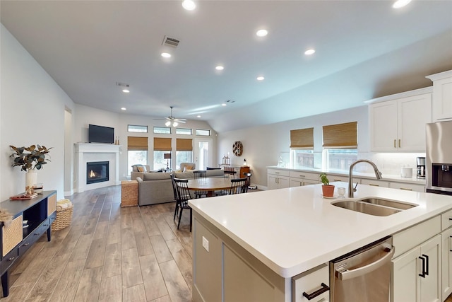 kitchen featuring sink, white cabinetry, light hardwood / wood-style flooring, appliances with stainless steel finishes, and a kitchen island with sink