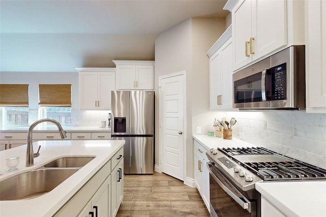 kitchen featuring sink, white cabinetry, light hardwood / wood-style flooring, stainless steel appliances, and decorative backsplash