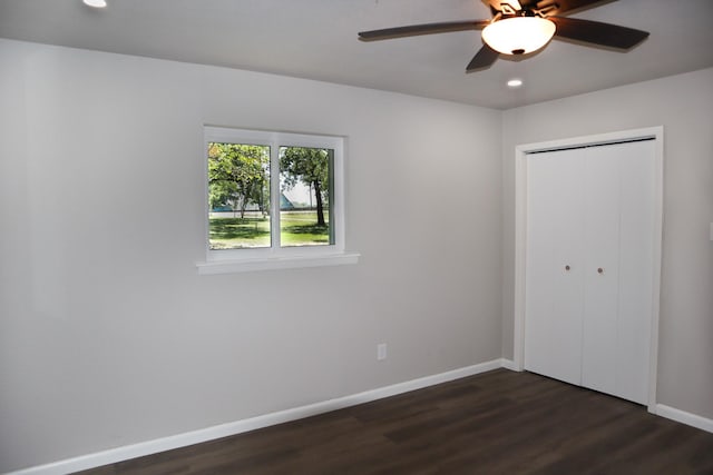 unfurnished bedroom with ceiling fan, dark hardwood / wood-style floors, and a closet