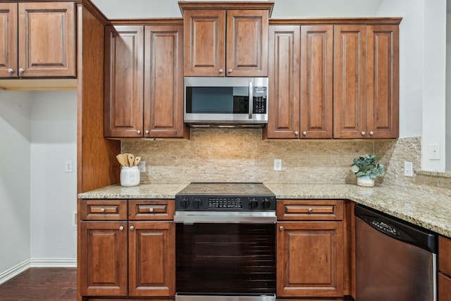 kitchen featuring tasteful backsplash, baseboards, light stone counters, brown cabinetry, and stainless steel appliances