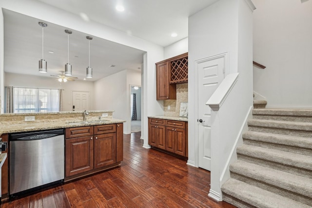 kitchen with tasteful backsplash, light stone counters, dishwasher, a sink, and dark wood-style flooring