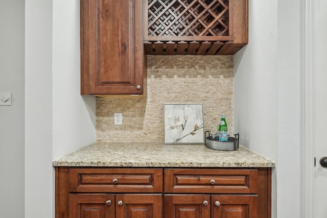 kitchen featuring light stone countertops, tasteful backsplash, and brown cabinets