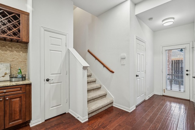 interior space with dark wood-style flooring, baseboards, and stairs