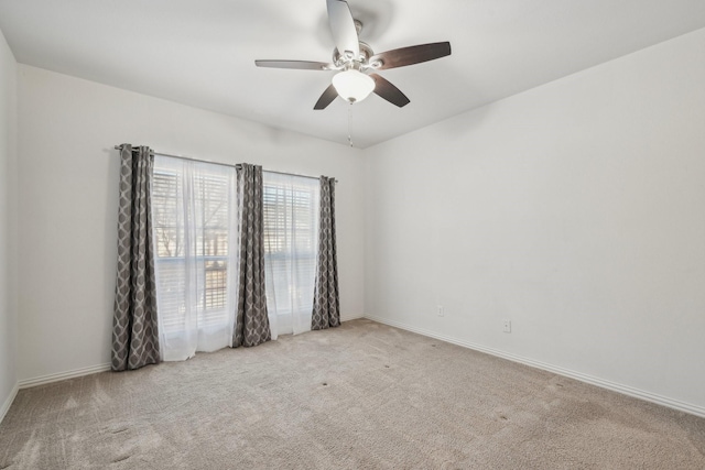 spare room with ceiling fan, baseboards, and light colored carpet