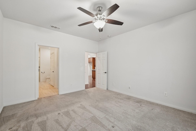 unfurnished bedroom featuring light carpet, baseboards, visible vents, ensuite bathroom, and a spacious closet