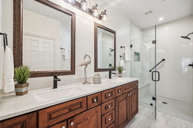 bathroom featuring a stall shower, visible vents, a sink, and double vanity