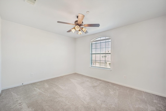 empty room featuring light colored carpet, ceiling fan, visible vents, and baseboards