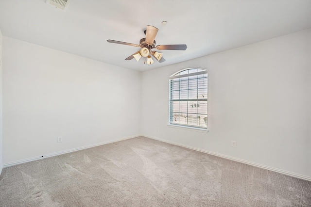 carpeted spare room with baseboards, a ceiling fan, and visible vents