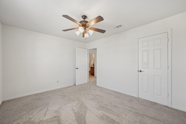 spare room featuring baseboards, visible vents, a ceiling fan, and light colored carpet