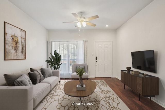 living area featuring baseboards, a ceiling fan, and wood finished floors