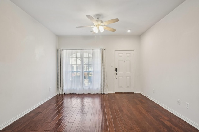 empty room featuring dark wood-style floors, baseboards, and ceiling fan