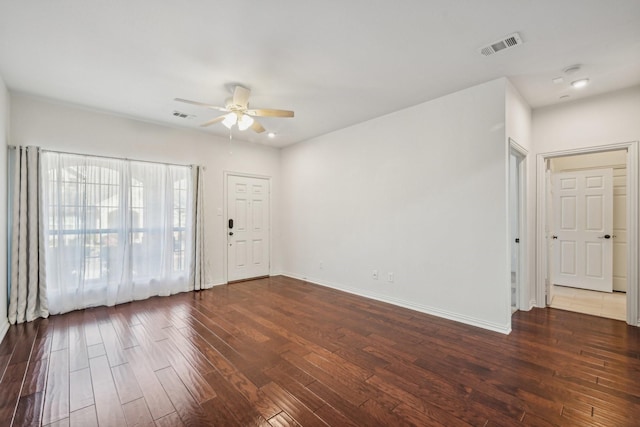 empty room with dark wood-style floors, baseboards, visible vents, and ceiling fan