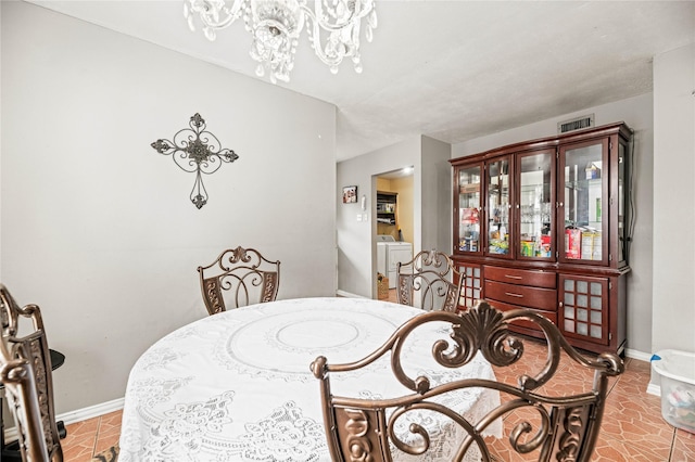 tiled dining space featuring washer / dryer and a chandelier