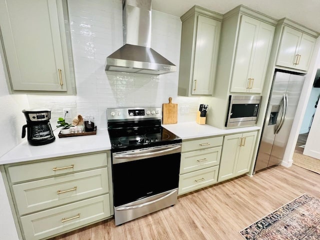 kitchen with appliances with stainless steel finishes, wall chimney exhaust hood, light hardwood / wood-style floors, and backsplash