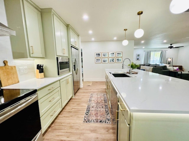 kitchen featuring sink, decorative light fixtures, a center island with sink, stainless steel appliances, and range hood