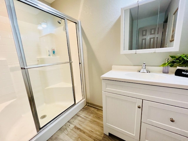 bathroom featuring vanity, hardwood / wood-style flooring, and a shower with shower door