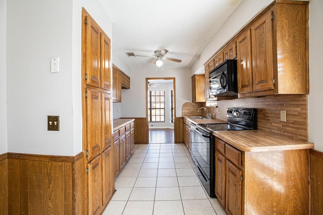 kitchen featuring brown cabinets, black appliances, light tile patterned floors, and light countertops