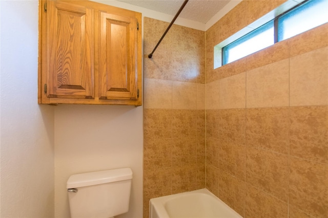 bathroom featuring tiled shower / bath, toilet, and a textured ceiling