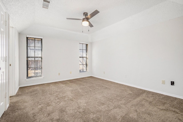 carpeted spare room with a textured ceiling, a ceiling fan, visible vents, and baseboards