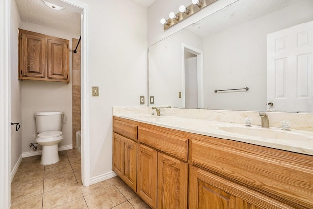 bathroom featuring double vanity, a sink, toilet, and tile patterned floors