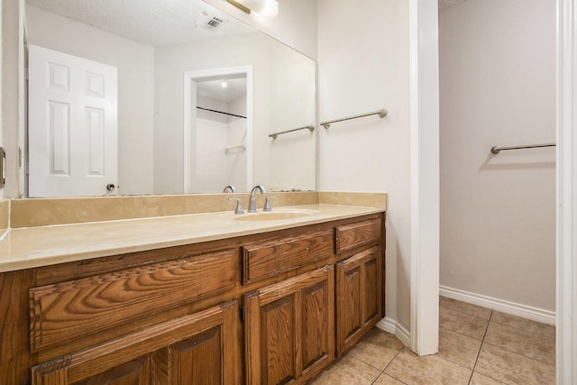 bathroom featuring visible vents, vanity, a textured ceiling, tile patterned flooring, and baseboards