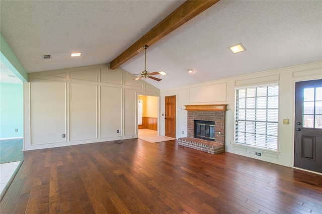 unfurnished living room featuring lofted ceiling with beams, hardwood / wood-style flooring, a textured ceiling, and a fireplace